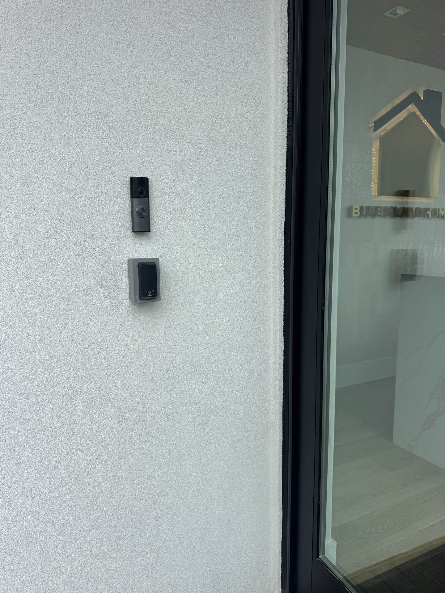 Video doorbell and Paxton access control card reader mounted at the entrance of a real estate office in East Hills, NY