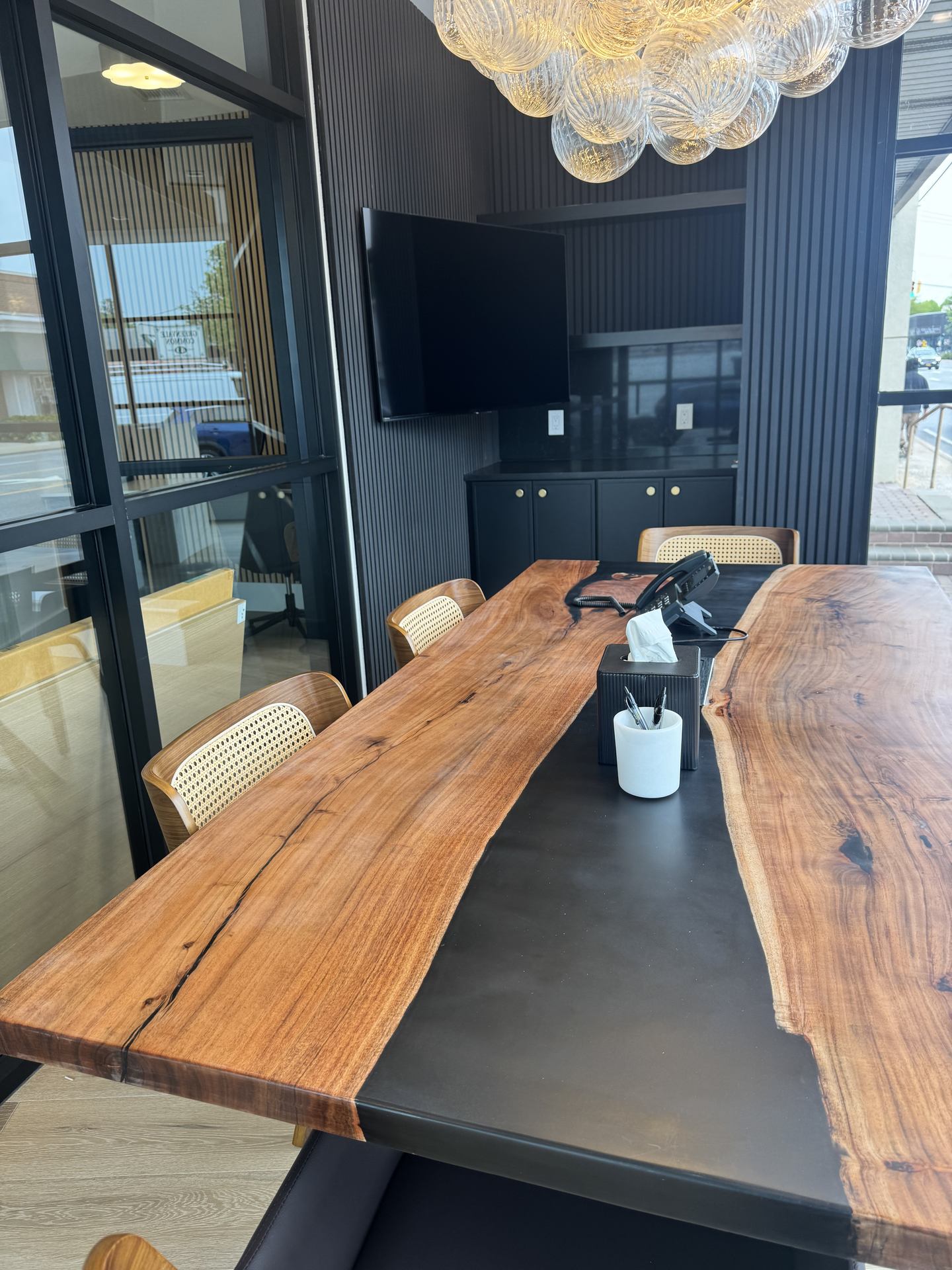 Wall-mounted conference room TV installed above a live-edge wood table in an East Hills, NY office